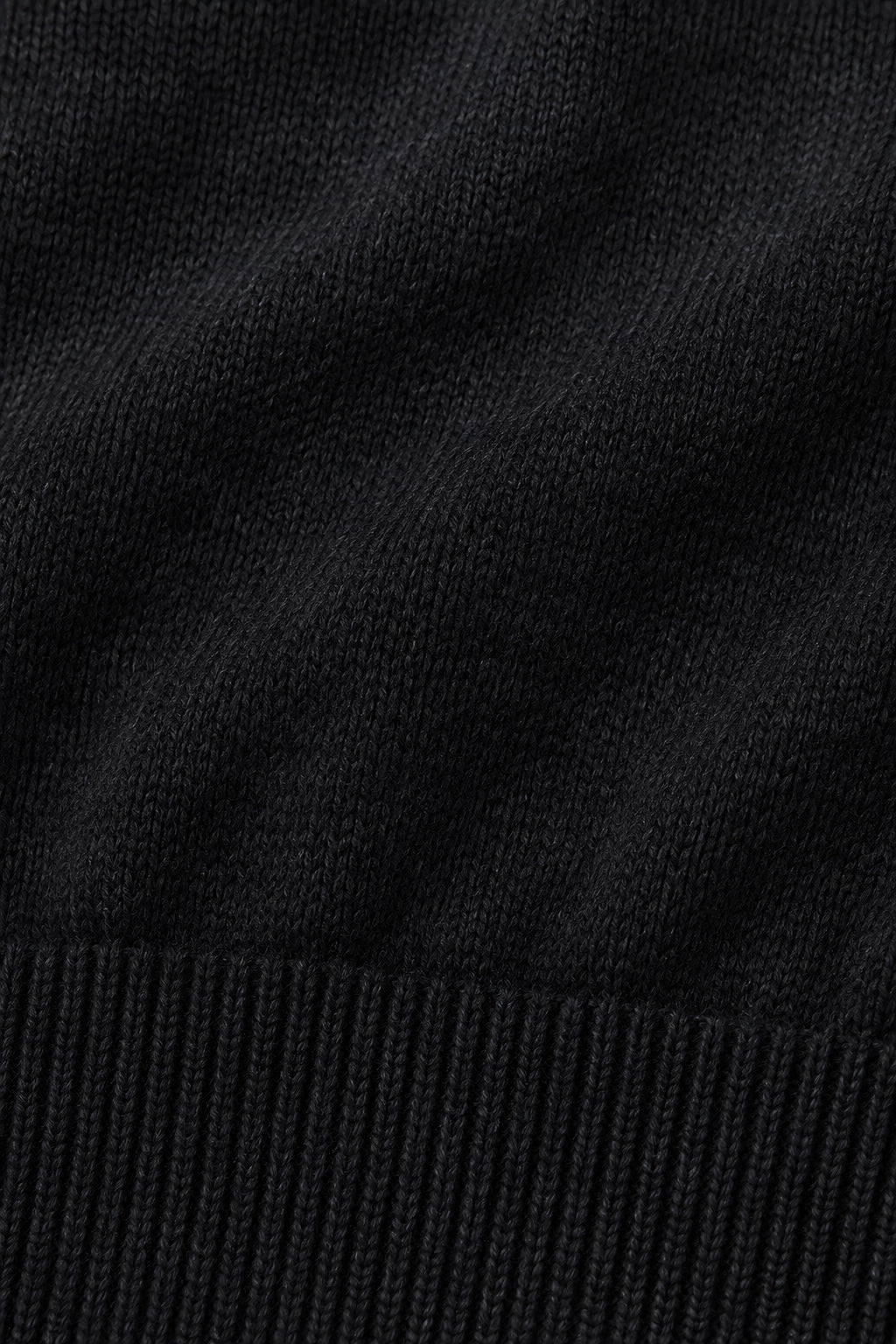 Pull col rond Socle noir, macro de la matière — visuel généré par IA