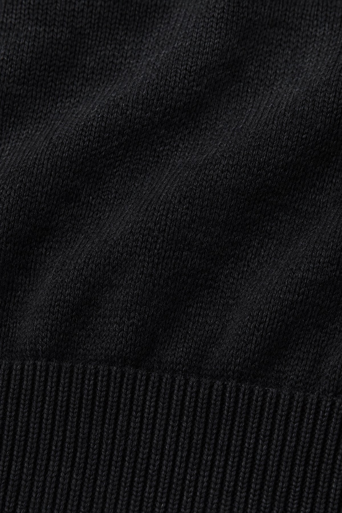Pull col rond Socle noir, macro de la matière — visuel généré par IA